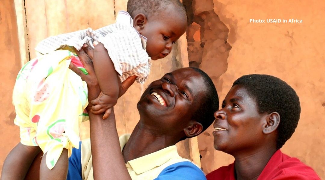 A smiling Malawi male and female couple hold a infant  