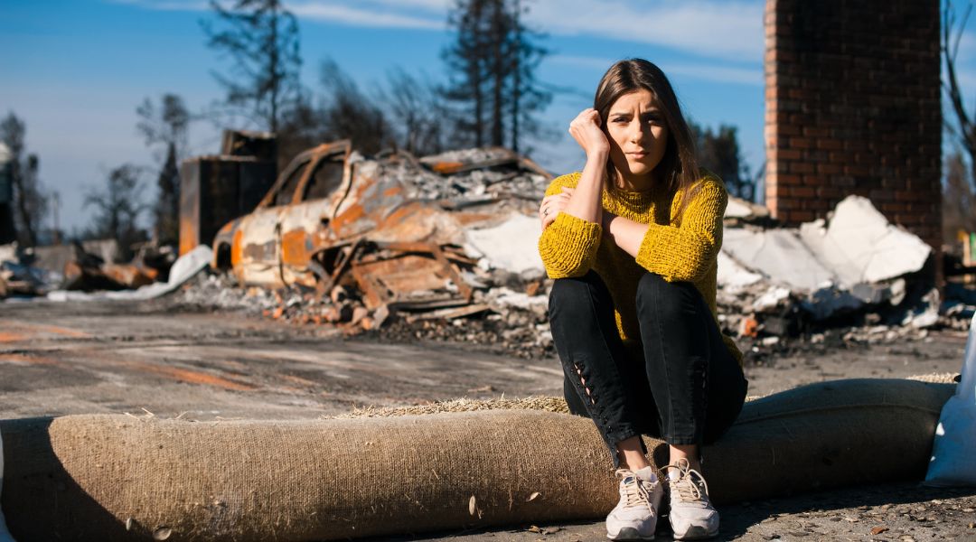 A woman sits among wildfire rubble