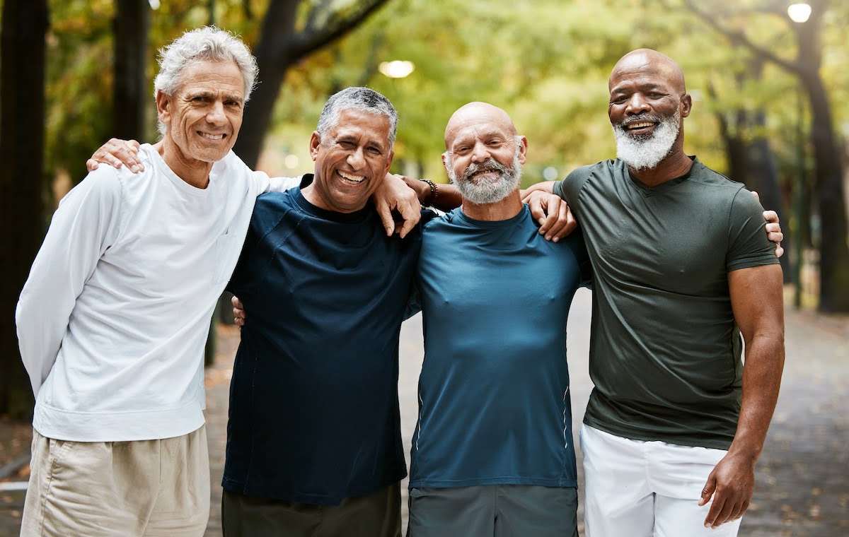 Four older men in friendship pose for a photo